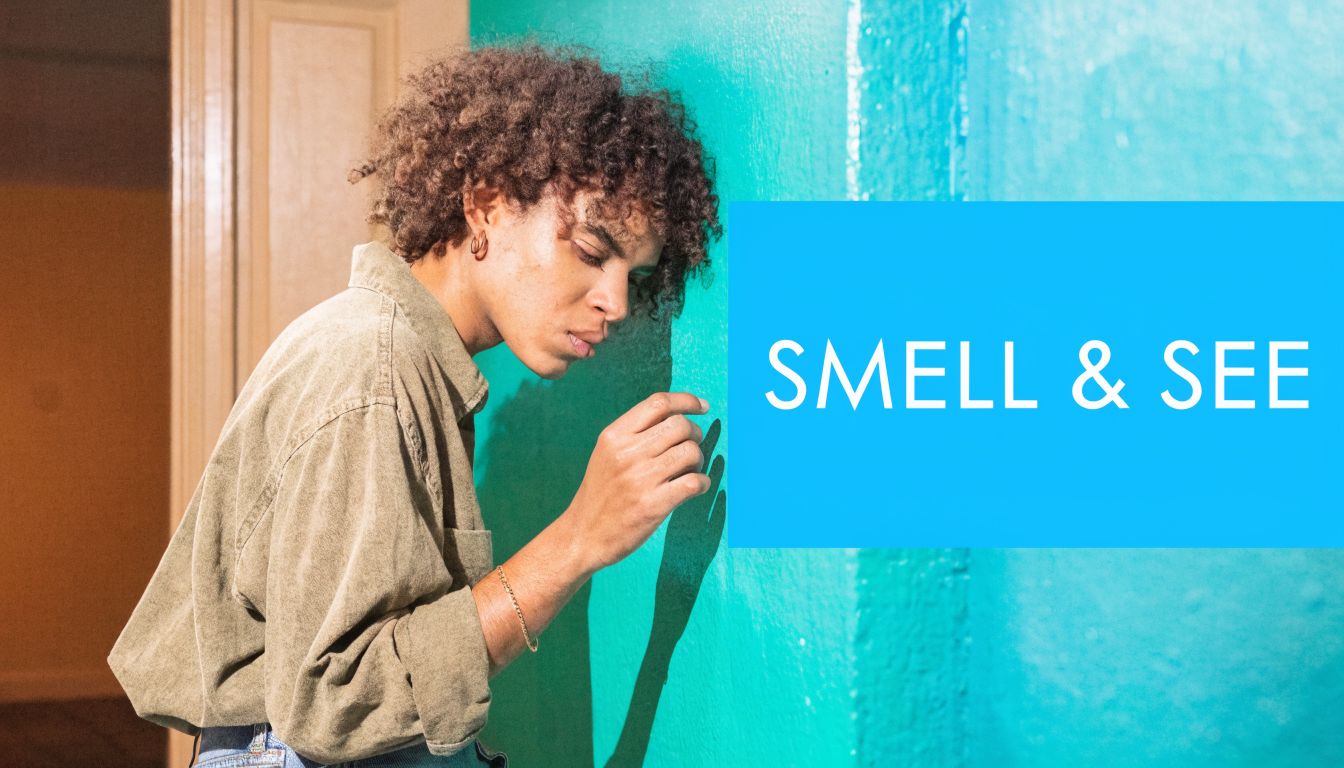 A person with curly hair leaning closely against a vibrant green wall to examine its surface.